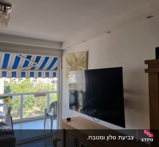 סלון עם טלוויזיה ומרפסת עם נוף ירוק